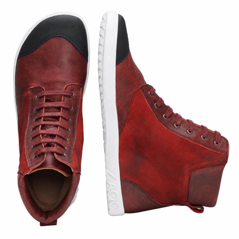 CHICAQO Red fra ZAQQ er et par high-top sneakers lavet af nappa- og ruskindslæder med sort tåkap og hvid, fleksibel sål. Den ene sko er udstillet oprejst for en sidevisning, mens den anden fremhæver sine snørebånd og det sorte frontdetalje ovenfra. Mærkenavnet ZAQQ er synligt på sålen.