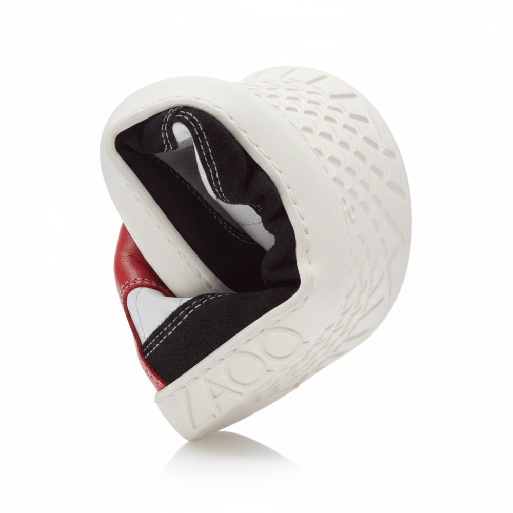 Der Schuh QAMPION Black White von ZAQQ verfügt über ein spiralförmiges Schneckenhaus-Design aus Veloursleder mit schwarz-weißem Schachbrettmuster, roten Akzenten, einer flexiblen Sohle und dem prominent an der Seite angebrachten Markennamen.