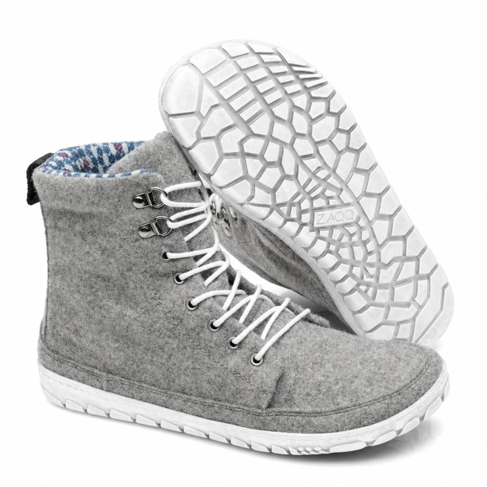 Udstillet er et par QICE Grey high-top sneakers fra ZAQQ med hvide snørebånd. Den ene sko står oprejst, mens den anden er vinklet for at fremhæve den strukturerede, mønstrede udendørssål.