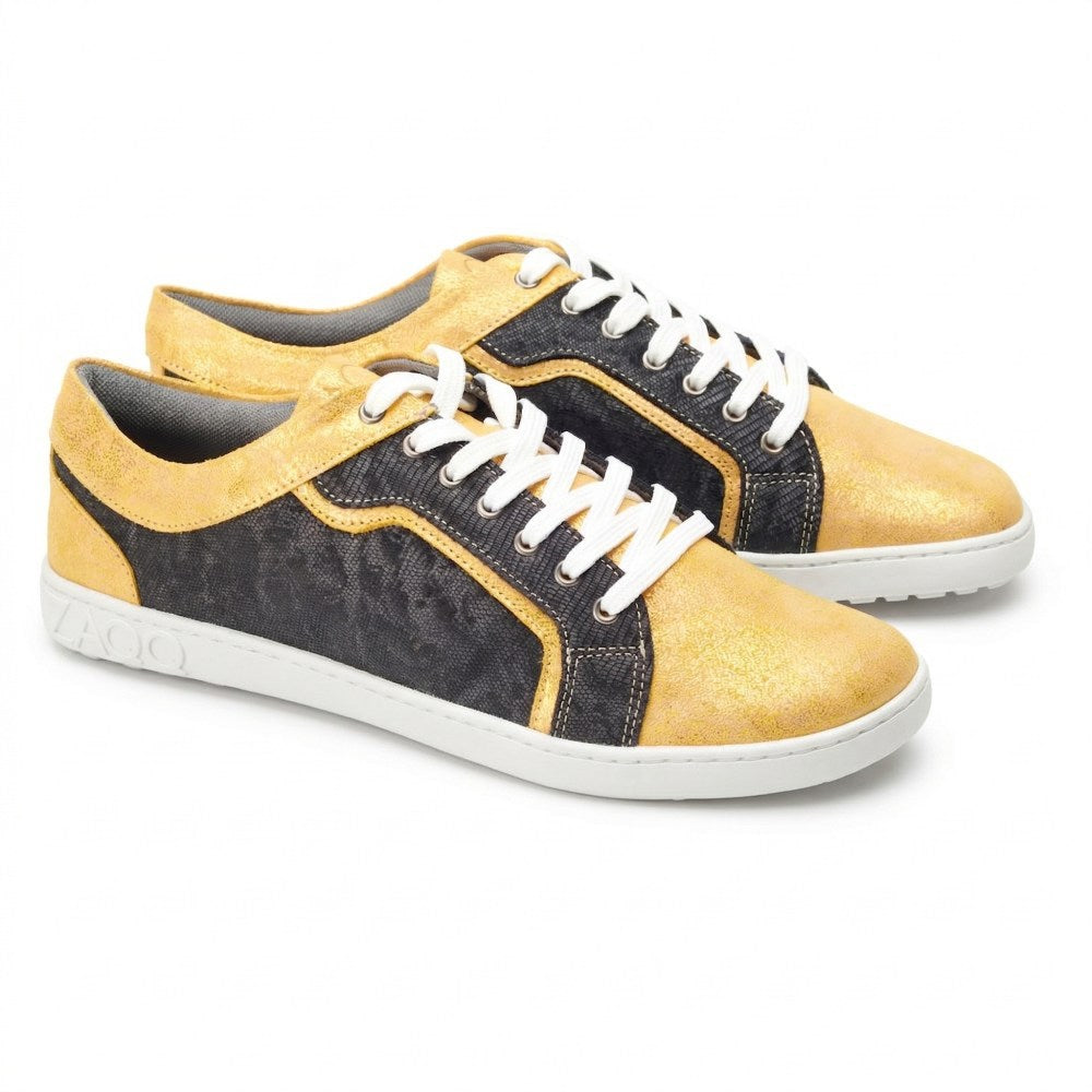 Wir präsentieren die QODY Gold Low-Top-Sneaker von ZAQQ, eine perfekte Mischung aus Stil und Komfort. Diese von Barfußschuhen inspirierten Schuhe präsentieren sich in schickem goldgelbem und schwarzem Farbblockdesign, gepaart mit weißen Schnürsenkeln und einer eleganten weißen Sohle mit ZAQQ-Prägung an der Seite, alles vor einem makellosen Hintergrund.