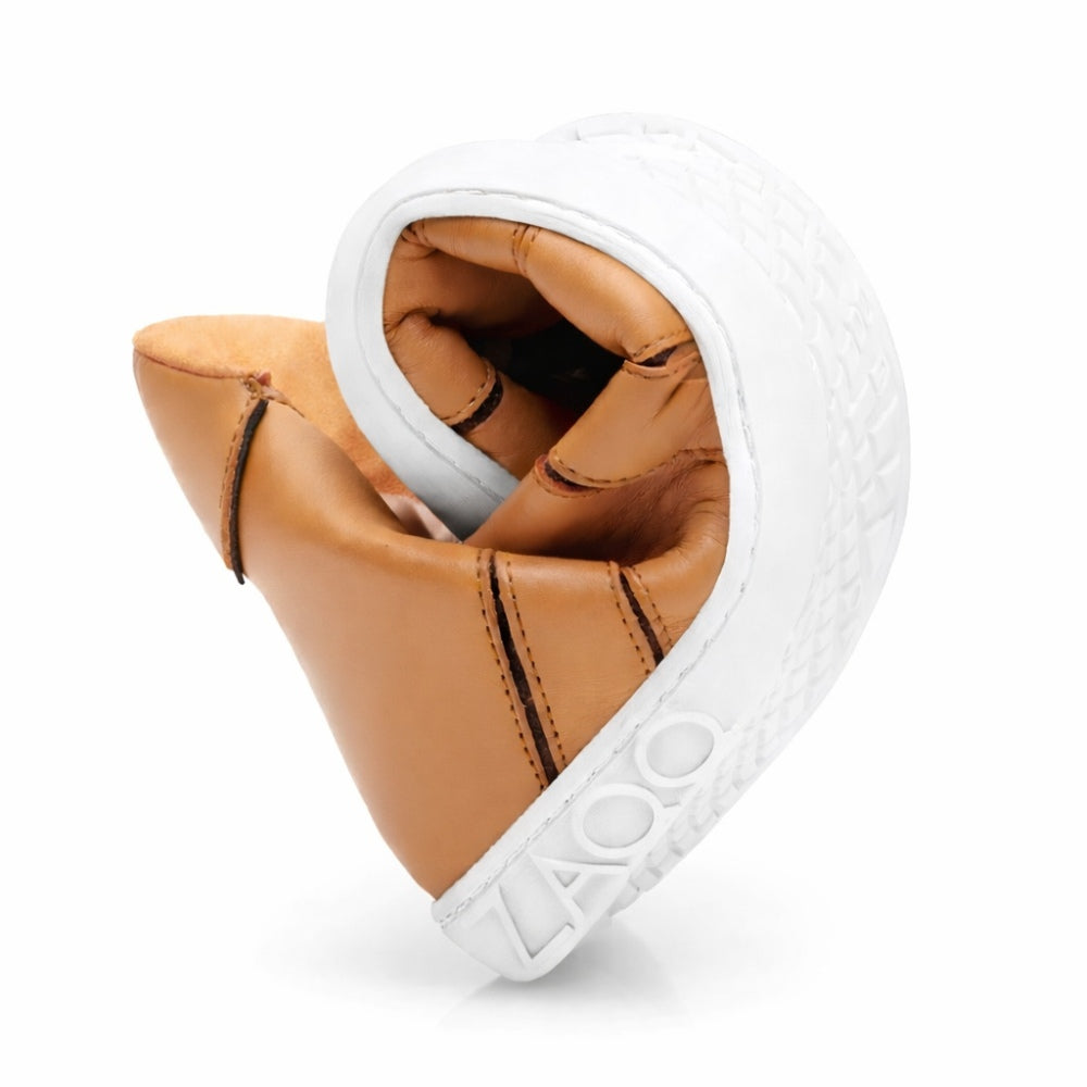 Die QQQ Mid Sierra-Schuhe von ZAQQ sind elegant in Herzform gedreht, was ihre bemerkenswerte Flexibilität unterstreicht. Diese hellbraunen Schuhe aus Nappaleder haben weiße Sohlen mit strukturierten Mustern, auf denen der Markenname ZAQQ eingeprägt ist. Erleben Sie das außergewöhnliche Barfußschuh-Tragegefühl bei jedem Schritt in diesen fachmännisch gefertigten Schuhen.