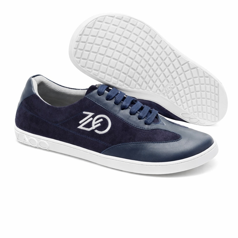 Wir präsentieren den Queensburry Marine von ZAQQ: ein Paar Barfuß-Sneaker in Dunkelblau mit weißer Sohle und Schnürsenkeln, gefertigt aus dunkelblauem Leder für verbesserten Komfort beim Laufen. Diese Schuhe verfügen über das ZAQQ-Logo an der Seite und ein strukturiertes Muster auf der sichtbaren Sohle, wodurch Stil und Komfort perfekt miteinander kombiniert werden.