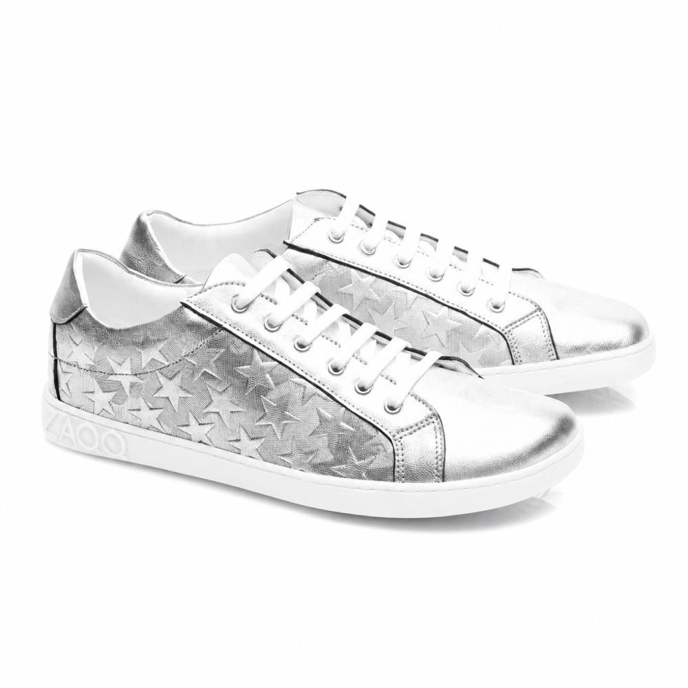 SLOQ Stars Silver-Sneakers fra ZAQQ har hvide snørebånd og stjernemønster på siderne, suppleret med en hvid sål med VAOO-prægning på hælen. Disse sko kendetegnes ved et slankt og moderne design med en skinnende metallic-finish.