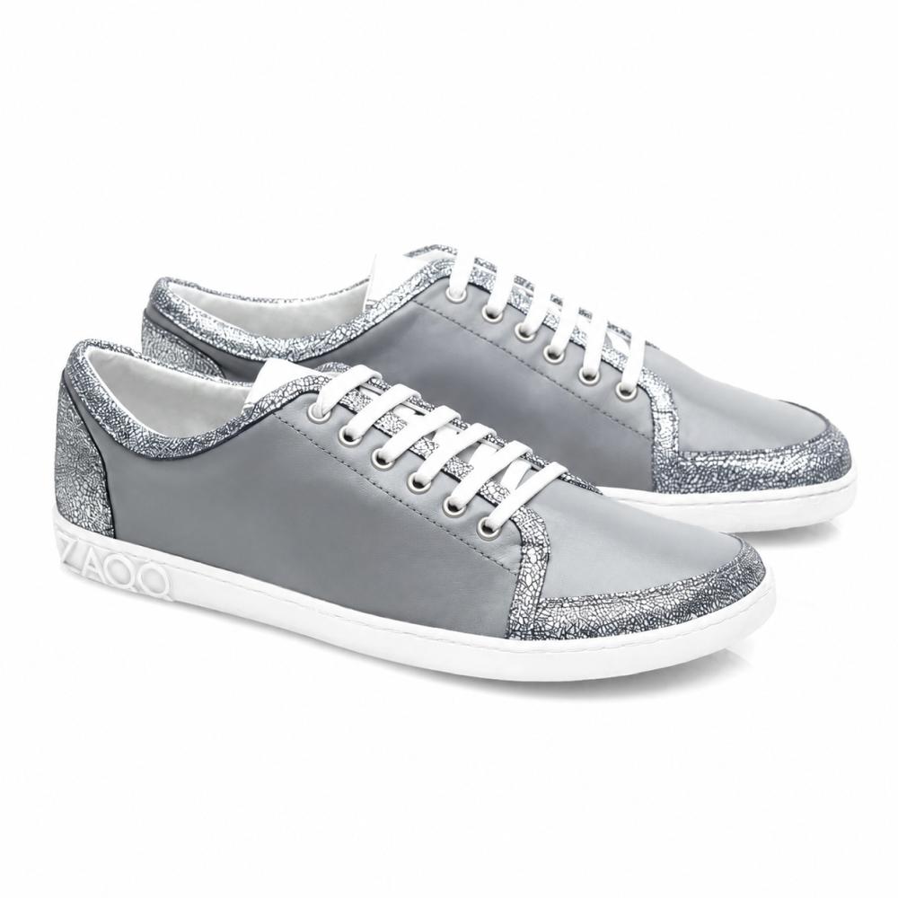 TIQQ Grey Silver Sneaker fra ZAQQ imponerer med deres enkle design af blødt nappalæder med hvide snørebånd og sølvglitrende accenter, suppleret med hvide såler og et diskret logo på hælen, og tilbyder den perfekte blanding af stil og komfort til enhver lejlighed.