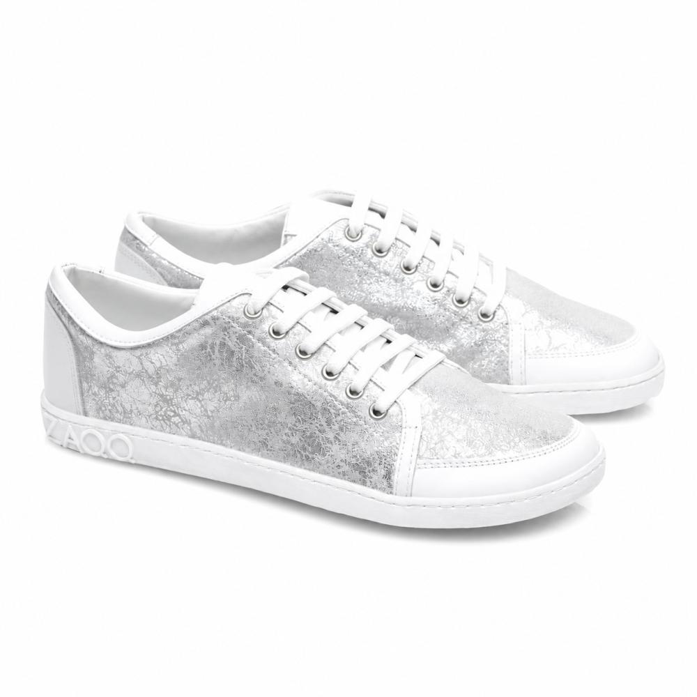 Vi præsenterer TIQQ Silver White fra ZAQQ: Et par stilfulde sneakers lavet af højkvalitets nappalæder med en iøjnefaldende metallisk-sølv tekstur og hvide såler. Disse sneakers er udstyret med strålende hvide snørebånd, dekorative syninger og en markant 4000-detalje på siden af sålen.