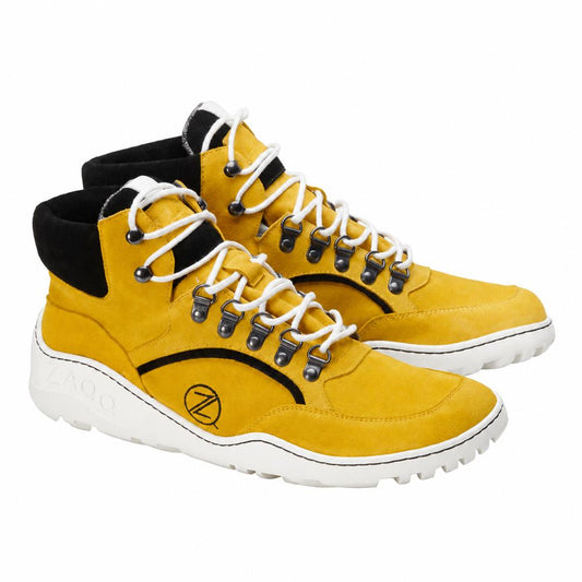 Ein Paar wasserdichte TREQ Yellow Wildleder-Wanderstiefel von ZAQQ mit weißen Schnürsenkeln, schwarzem Besatz und strapazierfähigen Gummisohlen. Inspiriert von Barfußschuh-Designs verfügen diese Stiefel über Metallösen und Ziernähte sowie ein markantes kreisförmiges Motiv an der Seite.